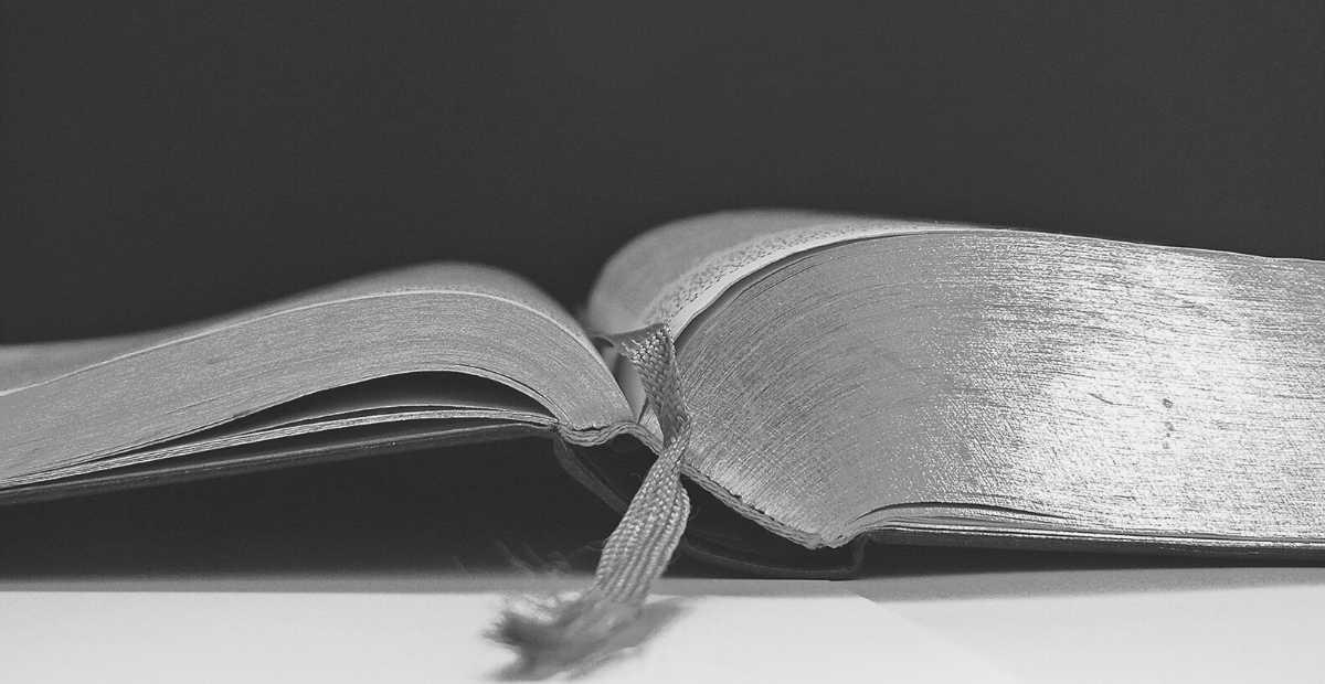 Black and white image of an open Bible to a bookmarked page.